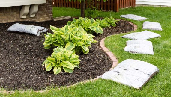 A garden featuring mulch spread across the ground, with several bags of mulch nearby.