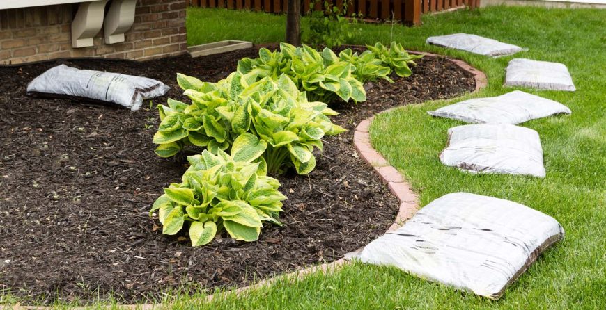 A garden featuring mulch spread across the ground, with several bags of mulch nearby.
